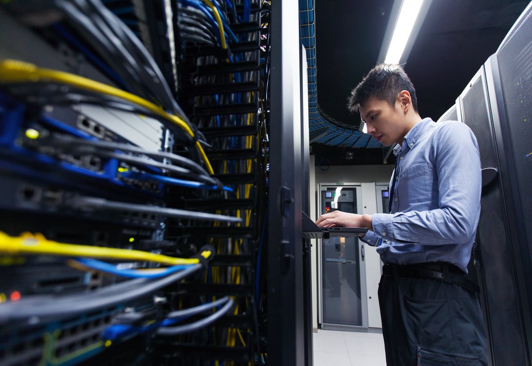 Young IT engineer inspecting data center servers